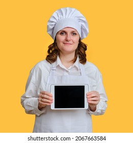 Happy Woman Chef Showing Ipad Apple Tablet Screen On Yellow Studio Background, Mockup Copy Space - Moscow, Russia, October 20, 2021