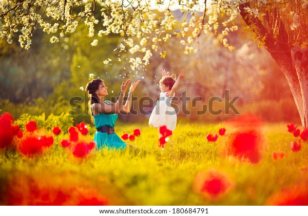  Happy woman and child in the blooming spring garden.Mothers day holiday concept
