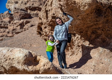 Happy Woman With A Child On The Hills Surrounded By Mountains. Mom And Kid In Charyn Canyon In Kazakhstan