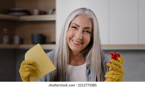 Happy woman clean worker older caucasian grandmother posing for camera in yellow rubber gloves hold in hands rag and spray bottle with clean liquid sanitizer having fun preparing for cleaning kitchen - Powered by Shutterstock