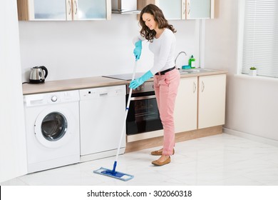 Happy Woman Cleaning Floor With Mop In Kitchen At Home