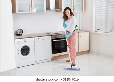 Happy Woman Cleaning Floor With Mop In Kitchen At Home