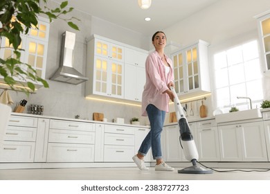 Happy woman cleaning floor with steam mop in kitchen at home, low angle view