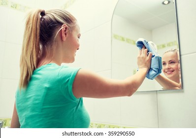 Happy Woman Cleaning Mirror With Rag