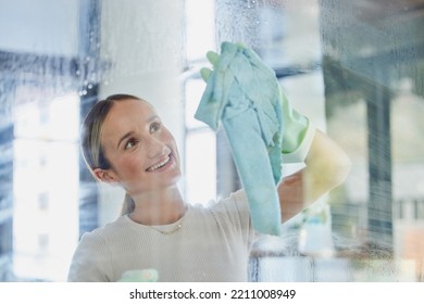 Happy, Woman And Cleaning Window In Home With Cloth To Wipe Away Water Mark With Proud Smile. Housewife Cleaner In Canada At Transparent Glass With Detergent Spray And Chemical Safety Gloves.