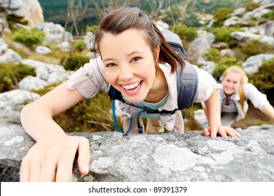 happy woman climbs a rock while trekking outdoors. carefree backpacker smiling at camera - Powered by Shutterstock