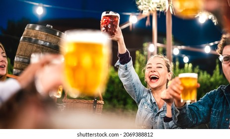 Happy woman clinking and toasting beer at brewery bar restaurant patio with friends - Life style and beverage concept with young people having fun together out side - Focus on face between glasses