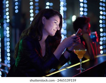 Happy, woman and cocktail in night club with cellphone at event, disco or concert for drink at bar. Female person, smile and waiting for date or friends at social, birthday or entertainment in London - Powered by Shutterstock