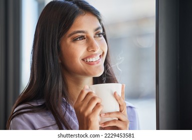 Happy, woman and coffee at a window for relax, thinking and daydream about future, goal and ideas in her home. Face, tea and indian girl smile in her living room, enjoy calm drink and window view - Powered by Shutterstock