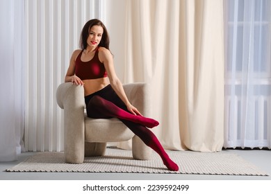 Happy woman in colorful gradient pantyhose sitting in chair and crossed legs