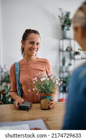 Happy Woman Communicating With Flower Shop Worker While Buying Potted Flowers. 