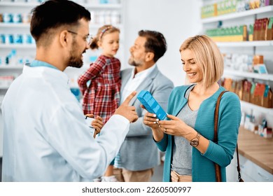 Happy woman communicating with pharmacist while shopping with her family in a pharmacy. - Powered by Shutterstock