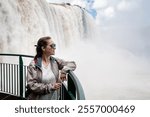 Happy woman contemplating the beautiful Iguazu Falls in Brazil. Iguazu Falls, Brazil. Young woman on vacation in Iguazú. Young woman enjoying the Iguazú Falls, Argentina