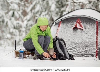 Happy Woman Cooking Near Winter Tent Camp In The Snow Forest. Bushcraft, Survival And People Concept