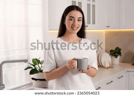 Happy woman with cup of drink in kitchen. Lazy morning