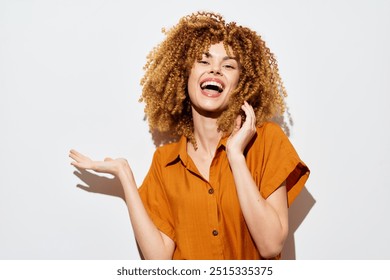 Happy woman with curly hair gesturing positively against a bright white background, showcasing joy and excitement in a casual outfit, embodying confidence and personality - Powered by Shutterstock