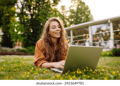 Happy woman with curly hair with a laptop outdoor.  Online education, Freelance work, technology concept. - Powered by Shutterstock