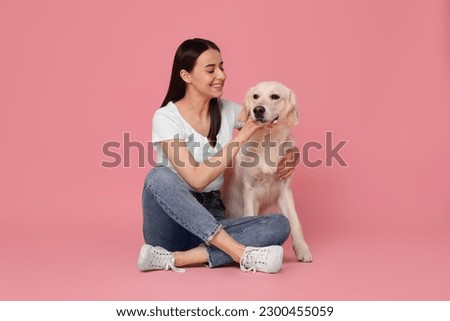 Happy woman with cute Labrador Retriever dog on pink background. Adorable pet
