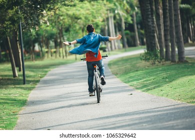 happy woman cyclist riding bike in spring tropical park - Shutterstock ID 1065329642