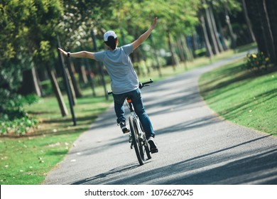 happy woman cyclist riding bike on tropical park - Shutterstock ID 1076627045