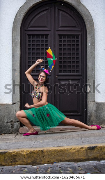 Happy woman dancing in the\
carnival of Brazil with the typical scenario of Olinda. Frevo\
dancing.