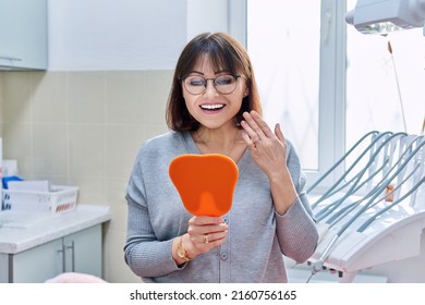 Happy Woman Dentist Patient With Mirror In Hands Looking At Her Teeth