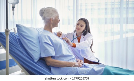 Happy Woman Doctor Check Up Body Or Heart By Stethoscope Of Sick Old Female Senior Elderly Patient Lying In Bed In Hospital Ward Room In Medical And Healthcare Treatment Concept. Caucasian People.