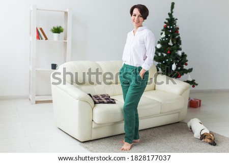 Happy woman with dog. Christmas tree with presents under it. Decorated living room