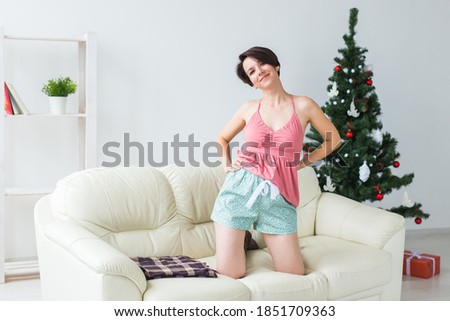 Happy woman with dog. Christmas tree with presents under it. Decorated living room