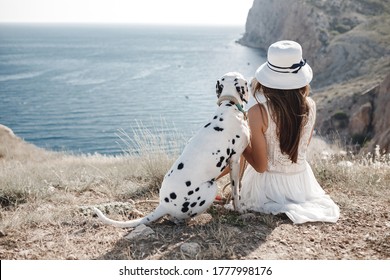 Happy woman with a dog dalmatian near the beach, backside