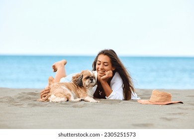 Happy woman with a dog relaxing on sand during summer vacation. Copy space.  - Powered by Shutterstock