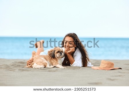 Happy woman with a dog relaxing on sand during summer vacation. Copy space. 