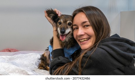 Happy Woman With Dog At Vet Clinic. The Owner And His Dog At A Treatment Room In A Veterinary Clinic. Pet Healthy Concept.