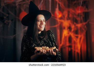 
Happy Woman Dressed In Witch Costume Holding Halloween Cookies. Cheerful Party Host Holding A Plate Of Biscuits 
