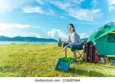 Happy Woman Drinking Alcohol While Camping At Meadow. People And Lifestyles Concept. Travel And Adventure Theme. Female Tourist Portrait