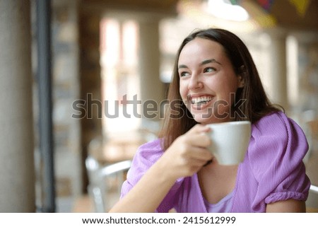 Happy woman drinking coffee and laughing looking away in a bar terrace