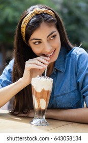 Happy Woman Drinking Cold Coffee While Sitting At Sidewalk Cafe