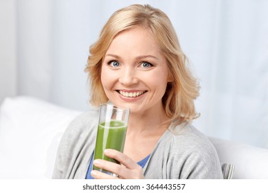 Happy Woman Drinking Green Juice Or Shake At Home