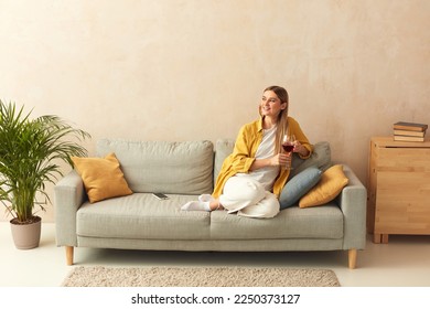 Happy Woman Drinking Wine At Home. Smiling Girl Relaxing On Sofa With Glass Of Red Wine At Home. Weekend Lifestyle Concept  - Powered by Shutterstock