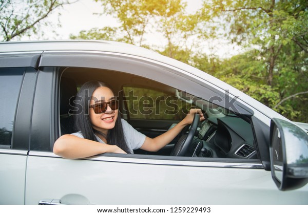 Happy woman drive car on summer roadtrip travel\
vacation leaning out car window. summer vacation, holidays, travel,\
road trip and people\
concept.