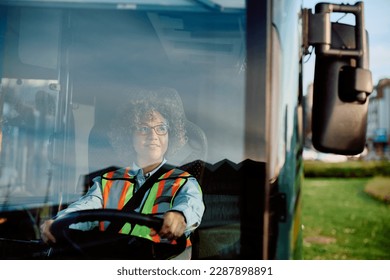 Happy woman driving a bus in reverse while looking at side view mirror.