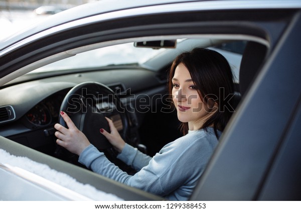 Happy woman\
driving a car outdoors in\
winter