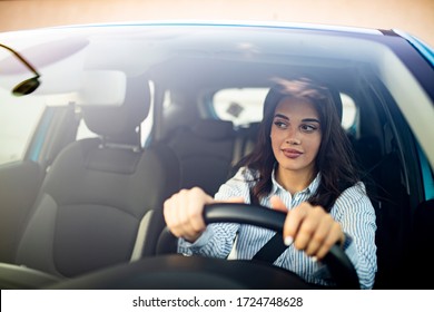Happy woman driving a car and smiling. Cute young success happy brunette woman is driving a car. Portrait of happy female driver steering car with safety belt - Shutterstock ID 1724748628