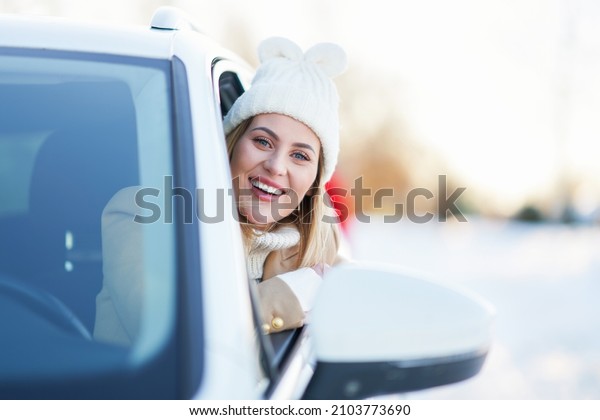 Happy woman driving car\
in snowy winter