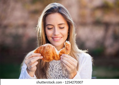 Happy Woman Eating A Croissant Outdoor