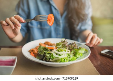 Happy Woman Eating Healthy Salad Sitting On The Table . Beautiful Girl Eating Healthy Food.