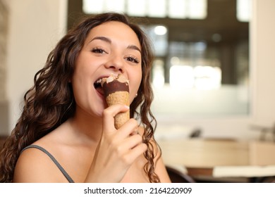 Happy Woman Eating Ice Cream Looking At You Sitting In A Bar Interior