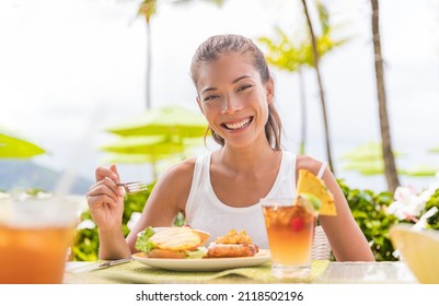 Happy Woman Eating Lunch At Outdoor Restaurant Terrace Plant Based Meat Burger With Pineapple. Hawaii Japanese Tropical Food. Asian Girl At Hotel Cafe Table During Summer Travel Vacation