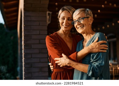 Happy woman embracing her senior mother on a terrace at sunset. Copy space. - Powered by Shutterstock