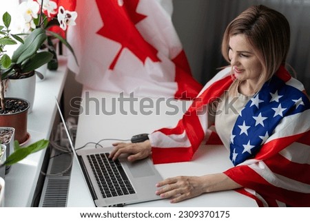 Happy woman employee sitting wrapped in USA flag, shouting for joy in office workplace, celebrating labor day or US Independence day.